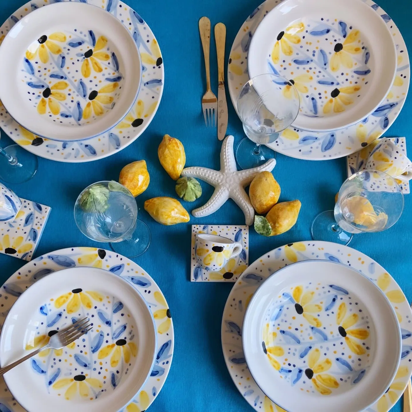 Una tavola apparecchiata con i piatti a margherite gialle e blu